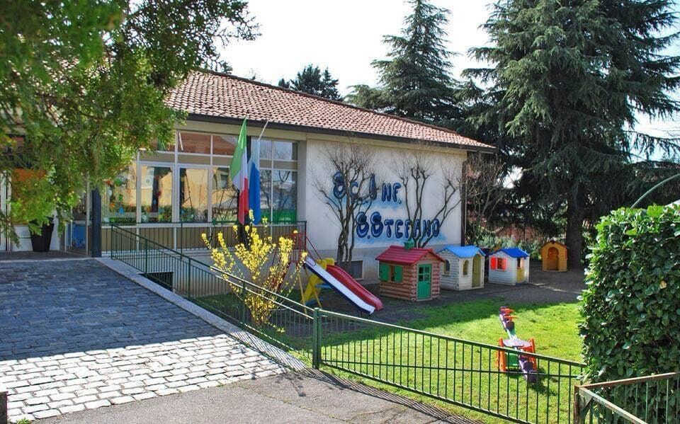L’ingresso della scuola e il giardino con scivolo, casette e alberi